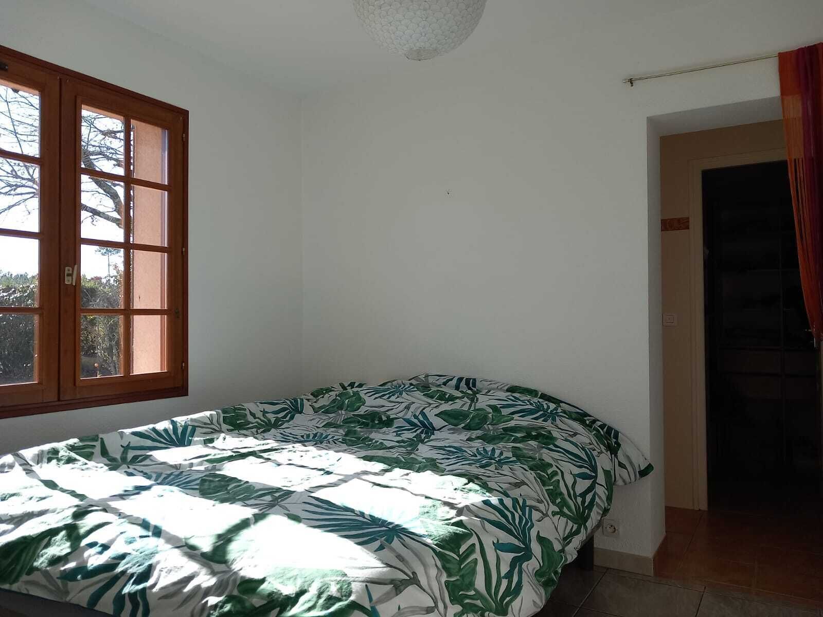 Een slaapkamer met een bed, een raam en een deur.