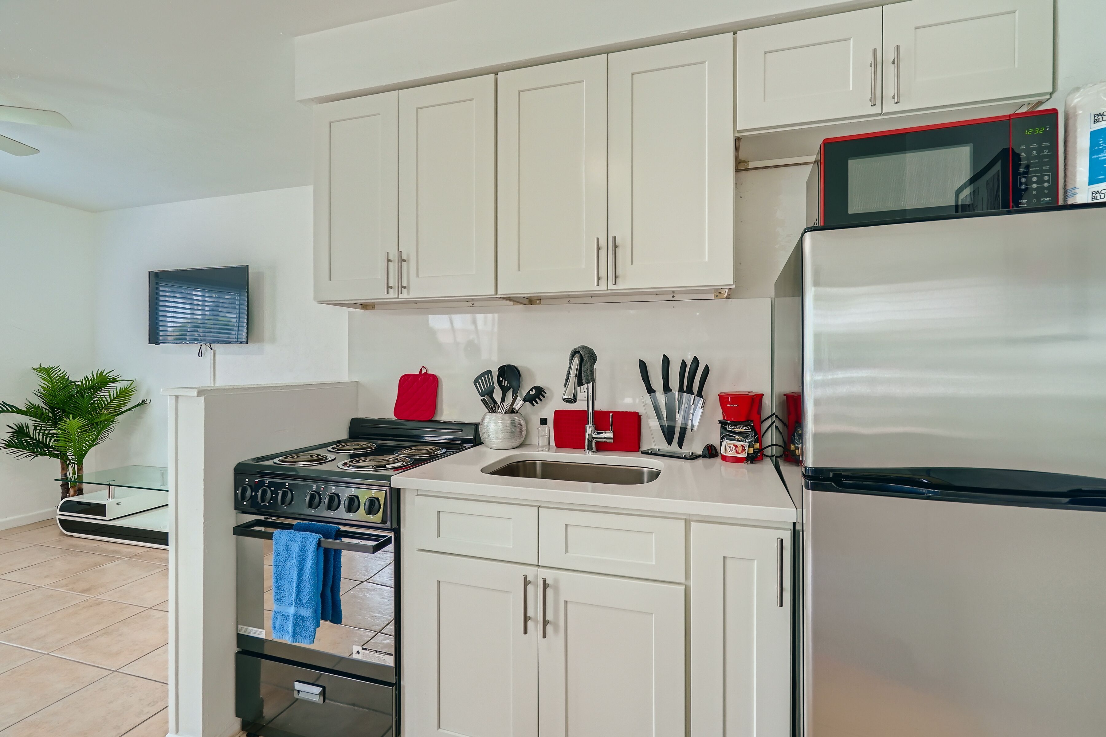 A modern kitchen with white cabinets, a stainless steel refrigerator, a microwave, and a gas stove.