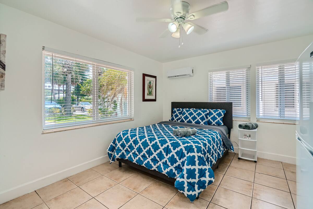 A bedroom with a bed, a ceiling fan, and a window with blinds.