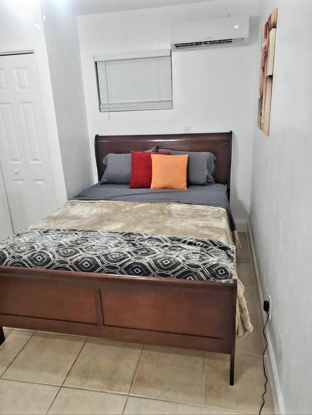 Une chambre à coucher avec un lit en bois, un matelas gris et une couverture à motifs.
