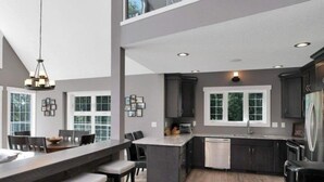 Una cocina moderna con una isla central, armarios oscuros y un amplio ventanal que proporciona luz natural.