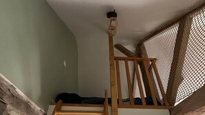 A loft-style room with a wooden ladder leading to a lofted bed area, a brick wall, and a window with curtains. - Joli Gîte de Campagne au Milieu des Champs - 4 à 8 Personnes (Neauphe-sur-Dive)