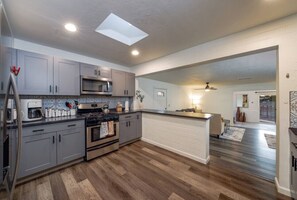 A modern kitchen with grey cabinets, stainless steel appliances, and a skylight. - Pool / Hot Tub / Huge Yard / 3 BR 3 BA / Fenced (Tucson)