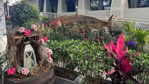 A garden with a wooden sign reading "Old Florida Fish House," surrounded by various plants and flowers. - Beachside Dreams, at Boutique Beachside Villas, Newly Renovated and Decorated (Santa Rosa Beach)