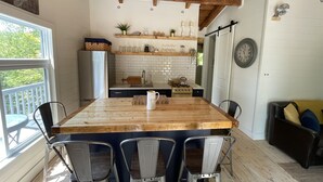 A kitchen with a wooden table, chairs, a stove, and a refrigerator. - The Bay Stay! Fully Renovated Off-Grid Waterfront Cottage on Burridge Lake  (Godfrey)