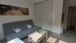 En moderne stue med en grå sofa, et hvidt sofabord og et billede på væggen.