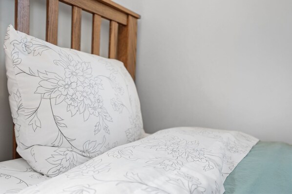 A bed with a floral-patterned pillow and a matching blanket. - A Winfield Bungalow (Dover)
