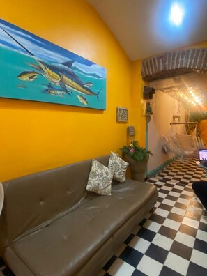 Relax in a stylish space with a leather sofa, potted plant, and a vibrant artwork above.