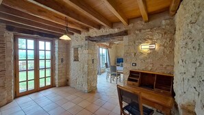 Una habitación rústica con paredes de piedra, vigas de madera y un ventanal grande.