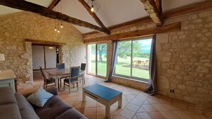 Un interior rústico con paredes de piedra, una zona de comedor y un amplio ventanal con vistas al exterior.