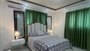 Un dormitorio moderno con una cama grande, cortinas verdes y una lámpara en el techo.