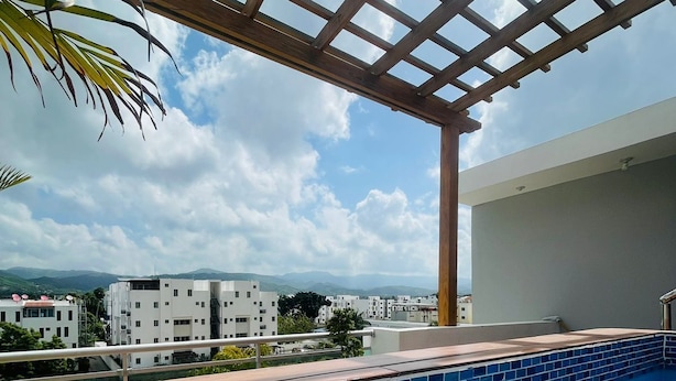 Una piscina en la azotea con terraza de madera y pérgola.