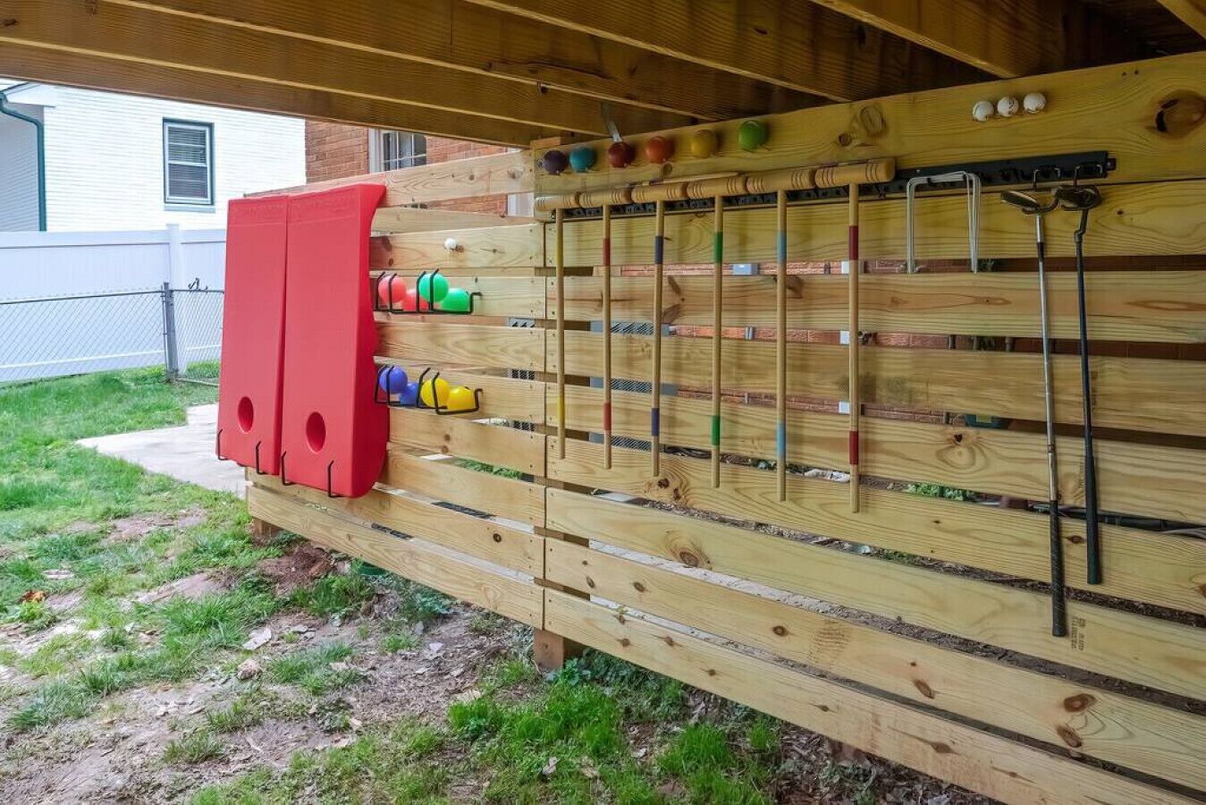 A wooden climbing wall with various colored holds and a red storage box.