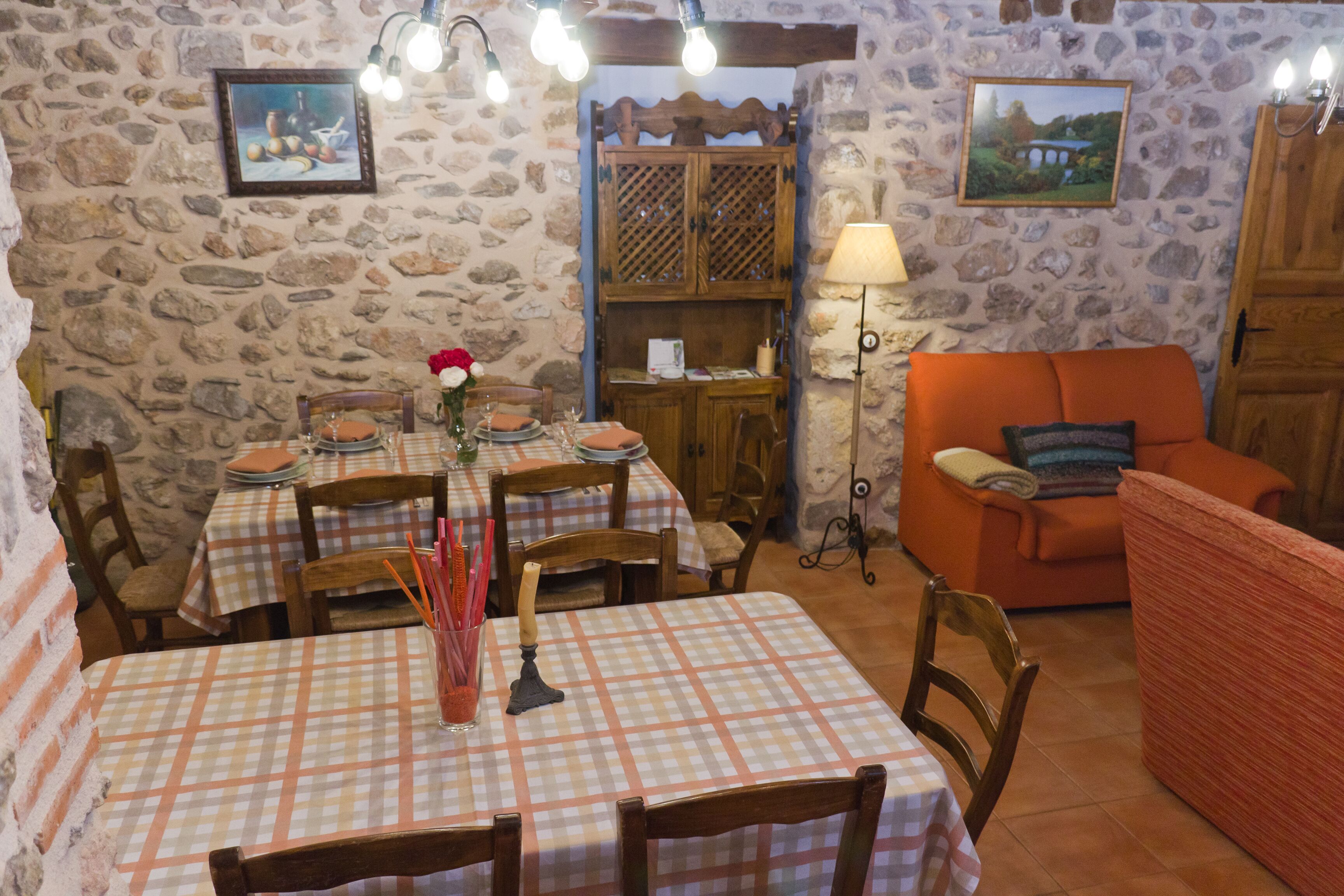 A dining area with checkered tablecloths, wooden chairs, and a stone wall.