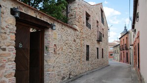 A narrow street with stone buildings, a wooden door, and a sign indicating a restaurant. - Casa La Plaza (Armuña)