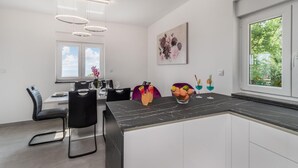A modern kitchen with a marble countertop, black chairs, and a dining table set for four.