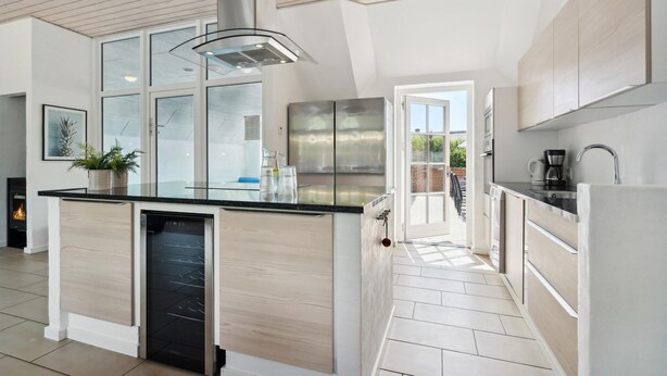 A modern kitchen with a central island, stainless steel appliances, and a view to the outside.