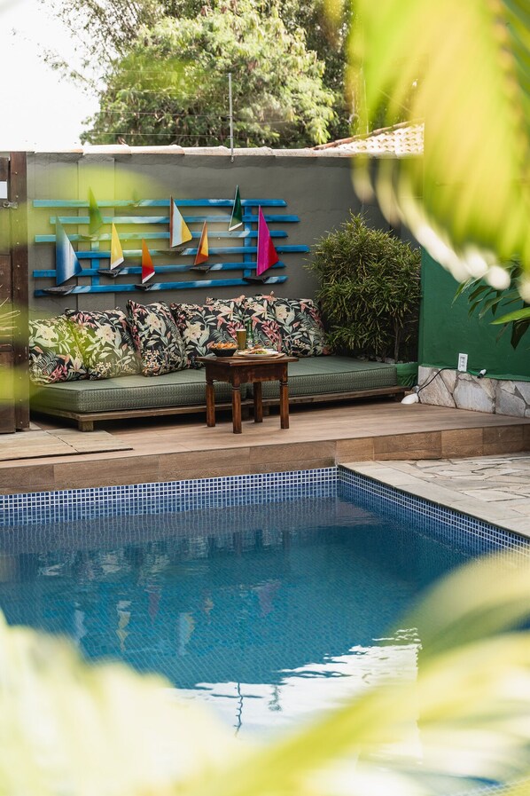 A pool area with a green sofa, colorful sailboat decorations, and a small table.