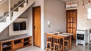 Una cucina moderna con piano cottura integrato, un tavolo da pranzo con sedie in legno e una TV fissata alla parete.