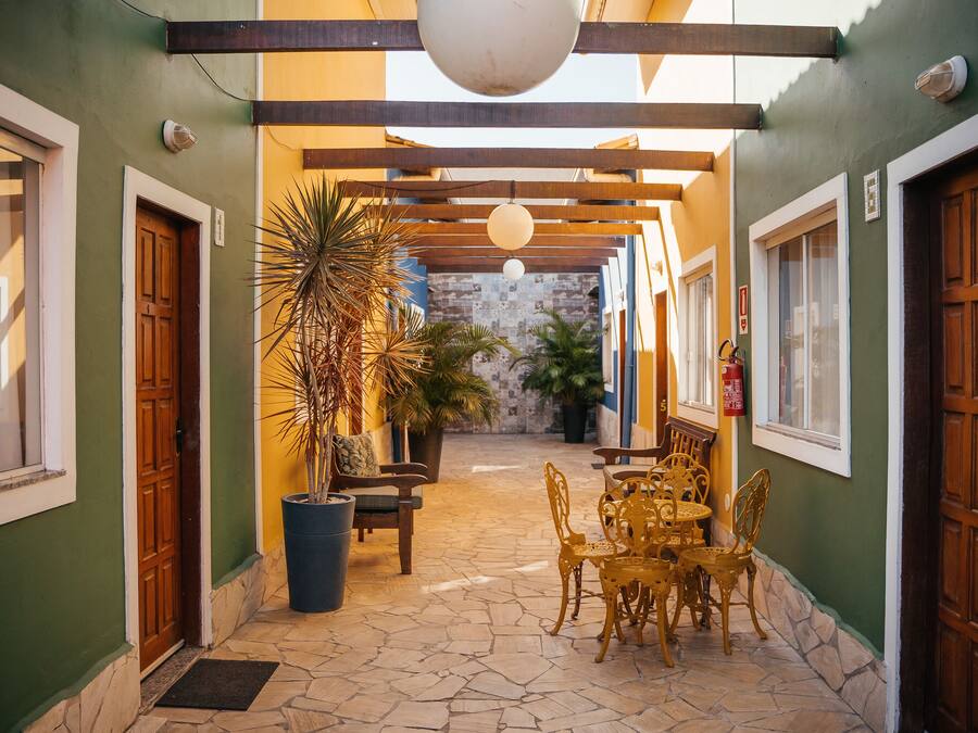 Un patio al aire libre cubierto con suelo de piedra, mobiliario de madera y plantas en macetas.