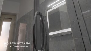 Un baño moderno con cabina de ducha de vidrio, puerta visible e iluminación en el techo.