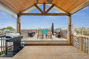 Une terrasse en bois avec un barbecue, des chaises et une table.