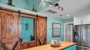 A kitchen with wooden cabinets, a blue countertop, and a stainless steel refrigerator. - Canalfront, Boat slip, Hot Tub, SUPs, Dogs, Beach (Destin)