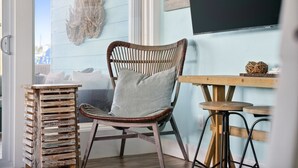 A wicker chair with a cushion, a wooden stool, and a small table with a woven basket. - Canalfront, Boat slip, Hot Tub, SUPs, Dogs, Beach (Destin)