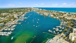 An aerial view of a coastal city with a marina, buildings, and clear blue waters. - Canalfront, Boat slip, Hot Tub, SUPs, Dogs, Beach (Destin)