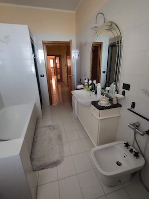 Un baño con bañera, lavabo, lavamanos y espejo.