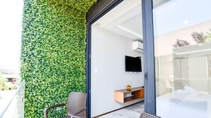 A balcony with a green wall, a flat-screen TV, and a wooden side table. - OP downtown studio by Casago (Playa del Carmen)