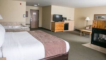 Ein Hotelzimmer mit einem großen Bett, einem Fernseher, einem Kamin, einem Schreibtisch und einem Badezimmer.