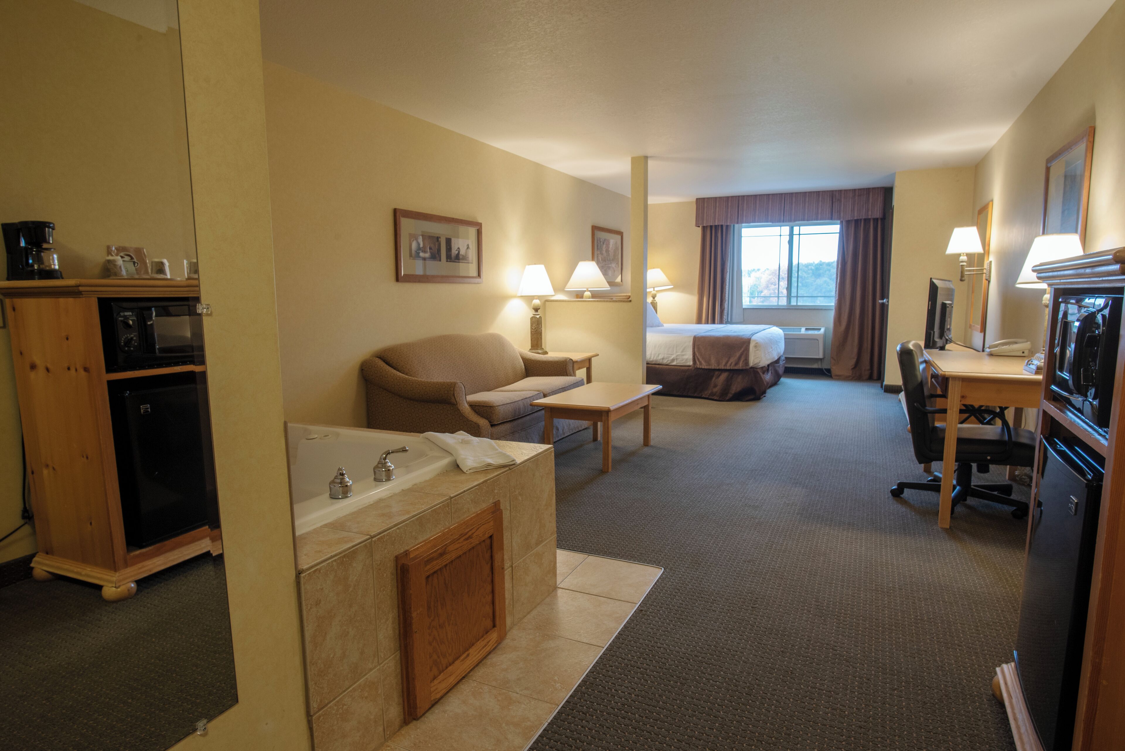 Ein Hotelzimmer mit Küchenzeile, einer Couch, einem Bett, einem Schreibtisch und einem Badezimmer.