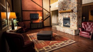 A spacious living room with a stone fireplace, leather furniture, and a television. - Thumper Pond Resort (Ottertail)