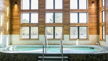 Uma área de spa com hidromassagem, degraus de pedra e grandes janelas.