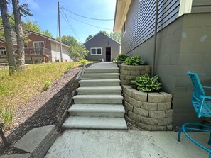 Stroll up to the front door, surrounded by lush greenery and a charming brick wall.
