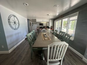 Enjoy meals in this spacious dining area with a long table for six, adjacent to a well-equipped kitchen.