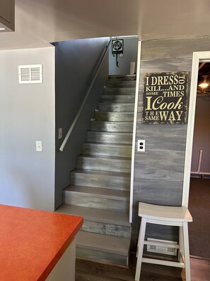 Stairs lead to an upper floor, with a sign above reading 'I DRESS THE WAY I KILL...AND SOME TIMES I COOK THE WAY'.