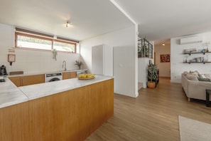 A modern kitchen with a wooden island, built-in appliances, and a dining area with a sofa and a coffee table.