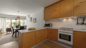 A modern kitchen with wooden cabinets, a built-in oven, and a dining area with a table and chairs.