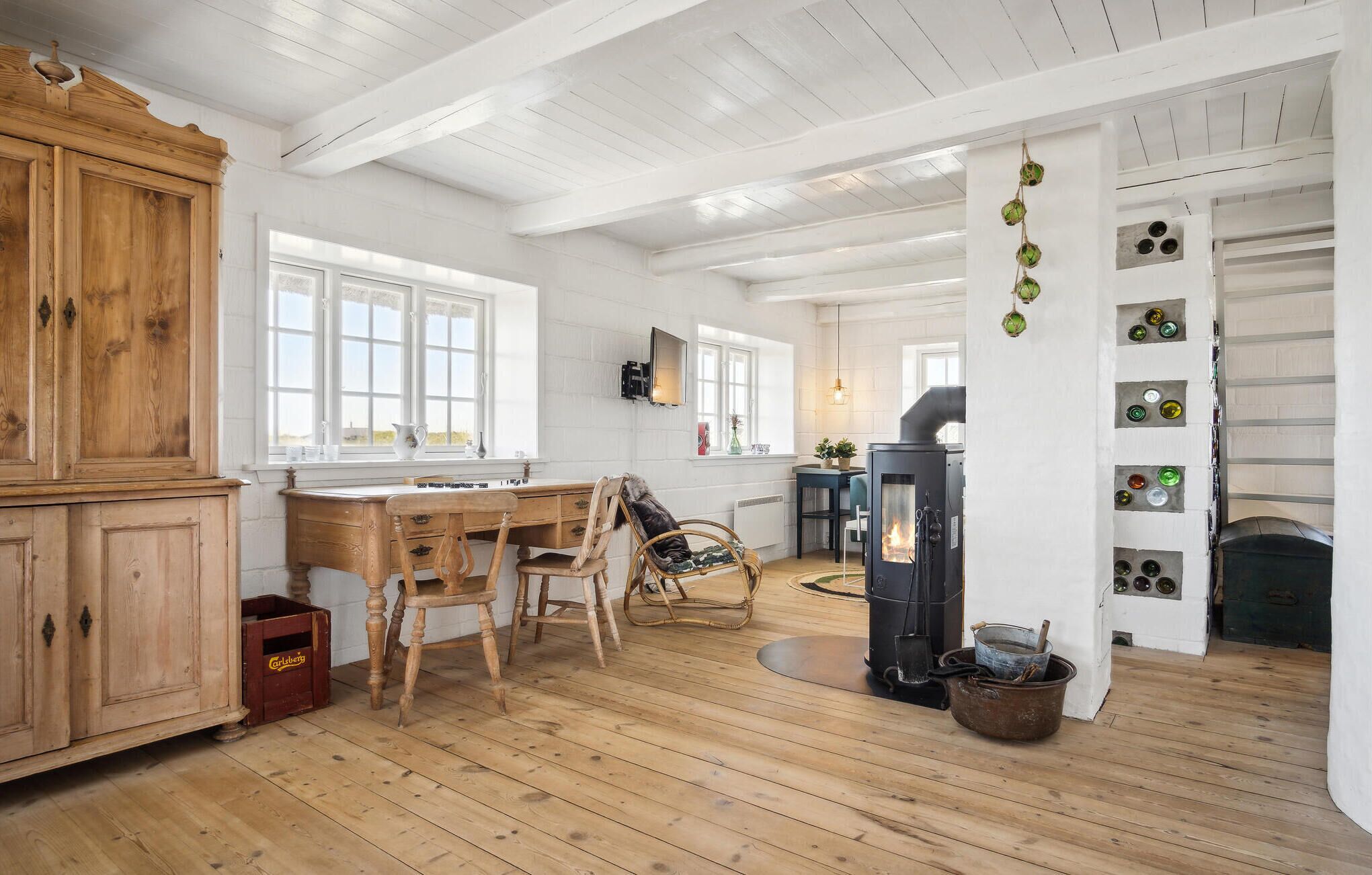 Une cuisine rustique avec des meubles de rangement en bois, une table à manger, des chaises, un fourneau et un porte-bouteilles fixé au mur.
