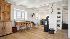 A rustic kitchen with wooden cabinets, a dining table, chairs, a stove, and a wall-mounted wine rack. - 3 bedroom gorgeous home in Blåvand (Blåvand)