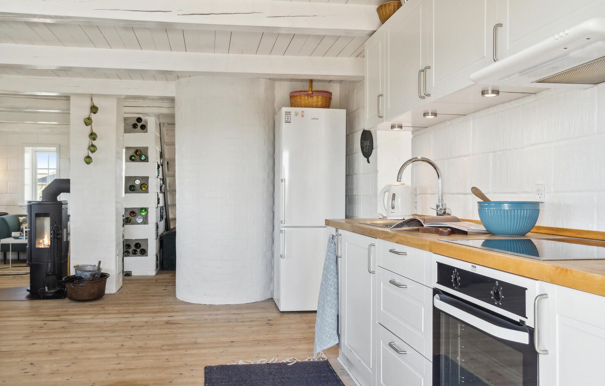 Une cuisine moderne avec des armoires blanches, un plan de travail en bois, un four encastré et une cuisinière noire.