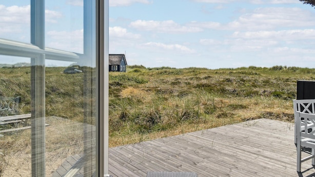 A wooden deck with a view of a house on a dune. - 3 bedroom gorgeous home in Blåvand (Blåvand)
