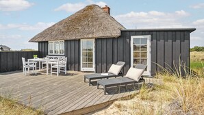 A thatched-roof building with a deck, outdoor seating, and a view of the surrounding landscape. - 3 bedroom gorgeous home in Blåvand (Blåvand)