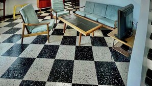 Een woonkamer met een geruit vloerkleed, een bank, fauteuils, een salontafel, een televisietoestel en een rode kast.