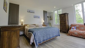 Une chambre à coucher avec un lit, une commode en bois, des tables de chevet et une fenêtre.