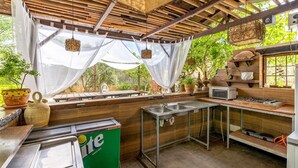 Una cocina exterior con estufa a gas, pileta y encimera de madera.