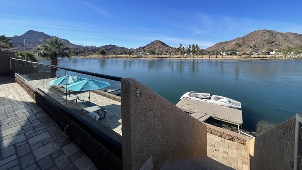 A view from a balcony overlooking a calm lake with mountains in the background.
