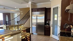 A modern kitchen with granite countertops, stainless steel appliances, and a dark wood cabinet.